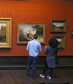 Two people standing in a painting gallery