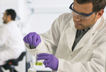 A student working in a lab wearing goggles and gloves