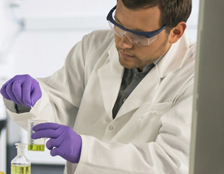 Student holding a beaker and wearing goggles