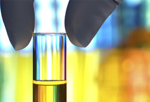 A test tube with a colorful background, and fingers hovering above it