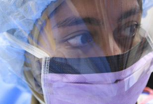 A student wearing a face mask, shield and hair covering in the lab