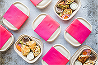 Containers with food, some open and some closed with pink wrapping.