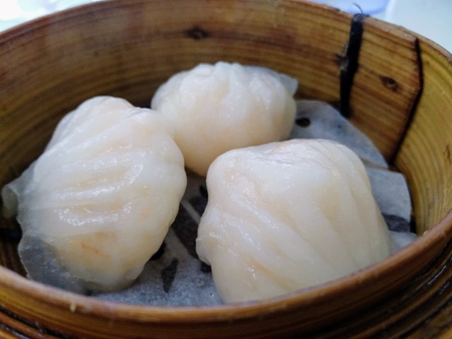 Three dim sum dumplings in a steamer basket