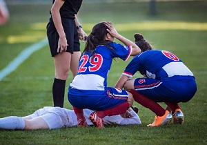 Soccer players surrounding injured athlete