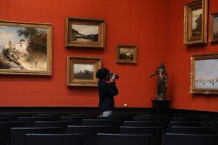 Person in art gallery taking a photograph with digital camera
