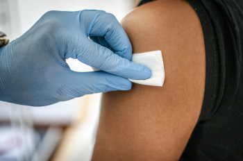 A provider swabbing a student's arm before giving a vaccine